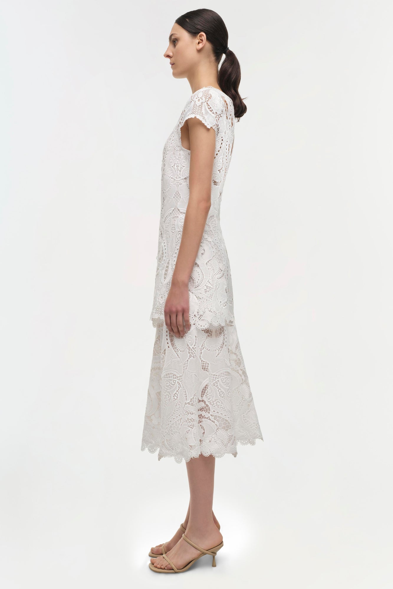 White lace midi dress with short sleeves and scalloped hem, shown on model in side view.