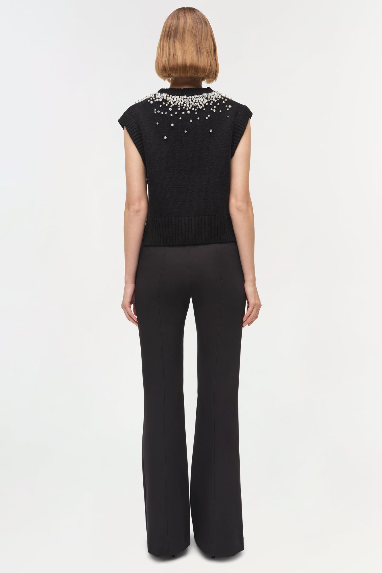 Black sleeveless knit vest with crystal embellishments across the shoulders and neckline.