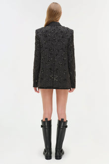 Black pinstriped blazer with scattered crystal embellishments throughout, worn with black knee-high boots.