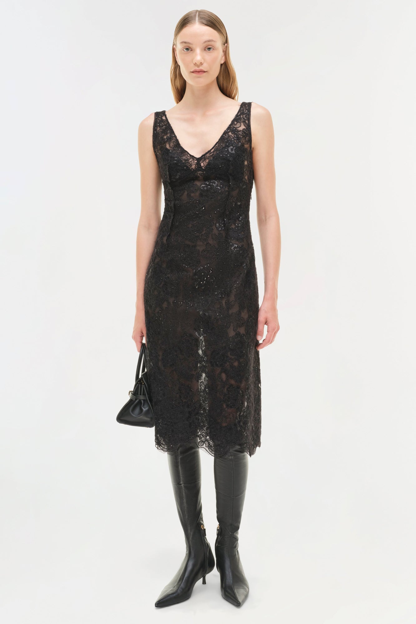 Black sequin lace sleeveless midi dress with V-neckline worn with black leather boots.