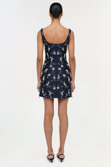 Navy sleeveless mini dress with white floral embroidered pattern and adjustable straps, shown from back view.