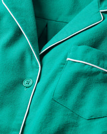 Close-up of a Womens Flannel Pajama top in Forest Green by Petite Plume with white piping. Made from 100% cotton twill, it includes a chest pocket and single button. The soft fabric promises warmth and comfort.