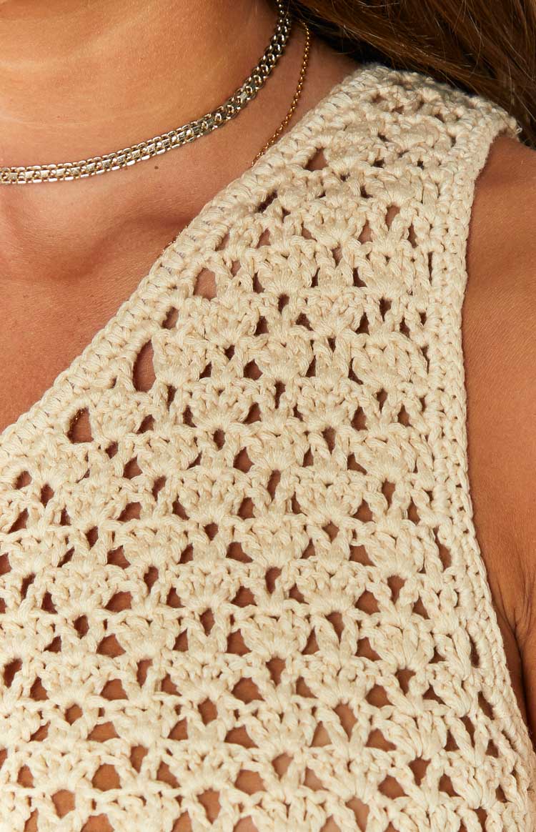 Close-up of the beige one-shoulder crochet mini dress showing the open knit pattern and mini length