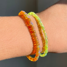 Shimmering Spring Green opal beaded bracelet made of smooth opals in shades of light yellow on a gold linking lobster clasp styled on a wrist with a orange opal bracelet