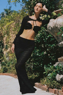 Black lace crop top with tie neckline and long sleeves, worn as part of a two-piece set.