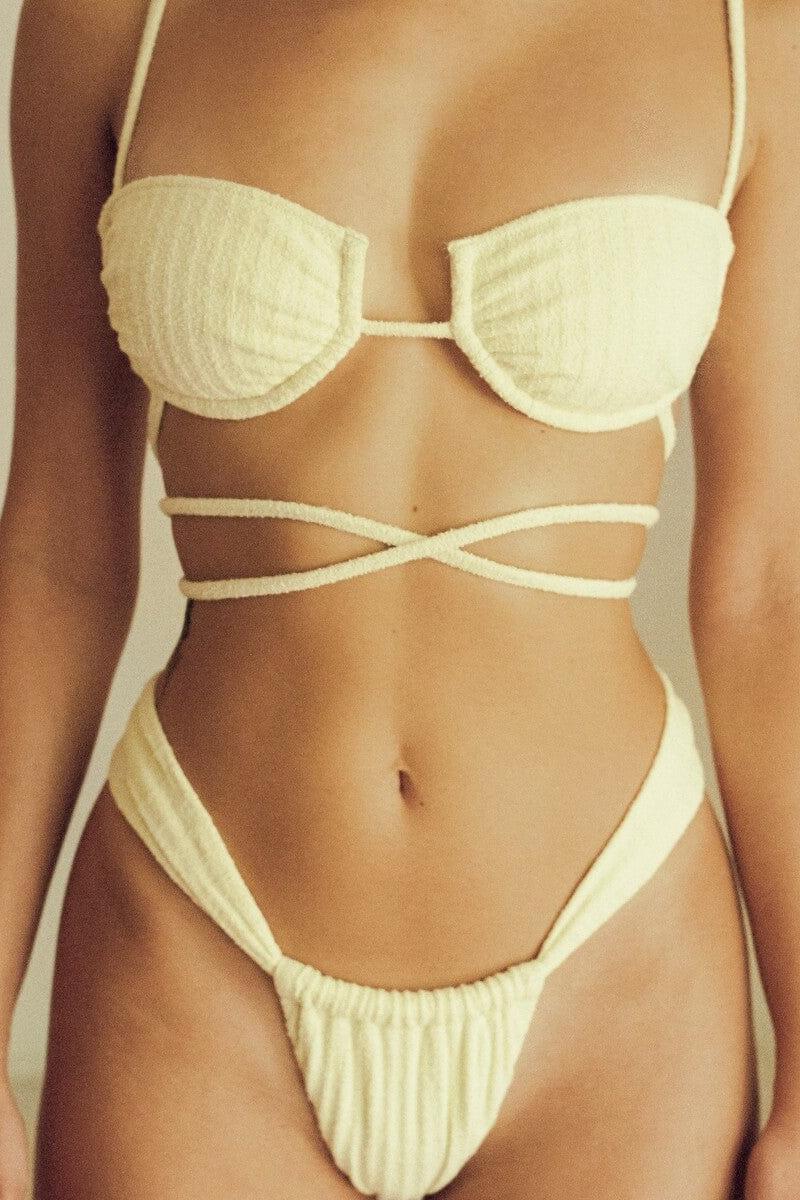 Cream ribbed bikini top with underwire cups and thin shoulder straps on model.