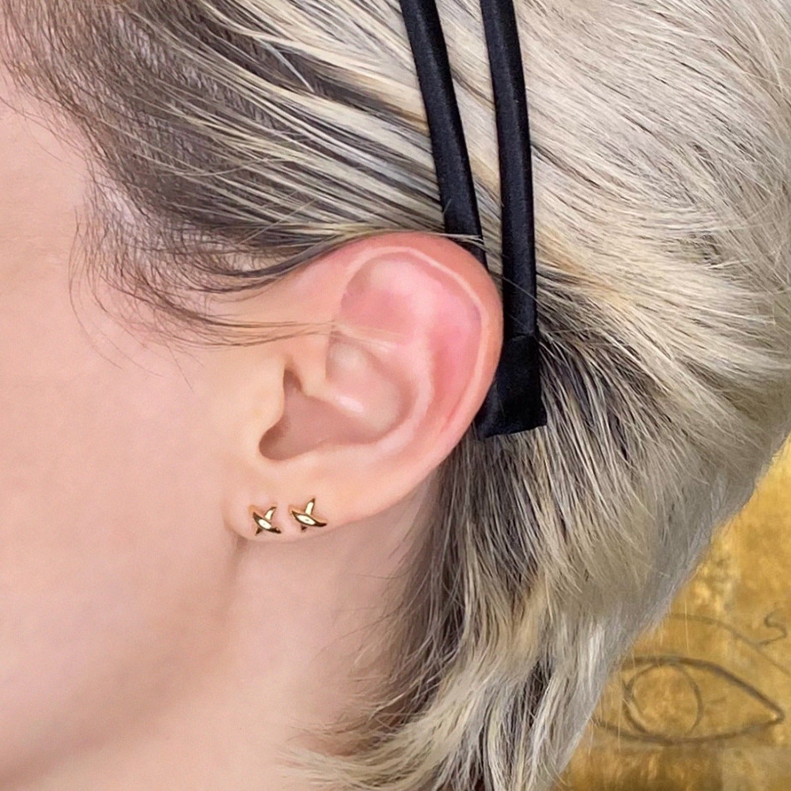 14k gold Stitch Stud Earrings styled together on an ear