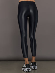 Model wears a mid rise waisted pair of liquidy shine black leggings that hit at model's mid to low calf.