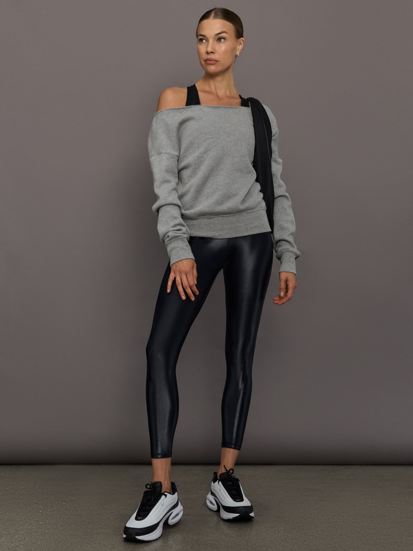Model wears a mid rise waisted pair of liquidy shine black leggings that hit at model's mid to low calf.