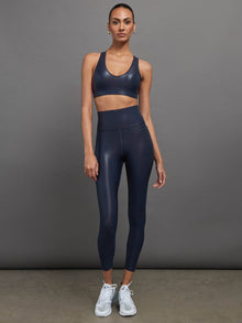 Model is wearing navy high waisted performance leggings in a liquidy-shine finish that hit at mid to low calf.