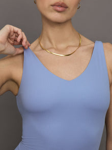 Model wears a periwinkle colored cropped v neck tank top with double straps on the back. 
