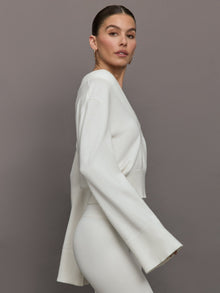 Model wears a white v neck bell sleeved sweater. 