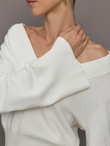 Model wears a white v neck bell sleeved sweater. 