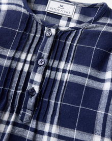The Girl's Brushed Twill Beatrice Nightgown in Oxford Tartan features a navy, white, and gray plaid pattern, long sleeves, a round neckline, front buttons, and pleats near the chest.