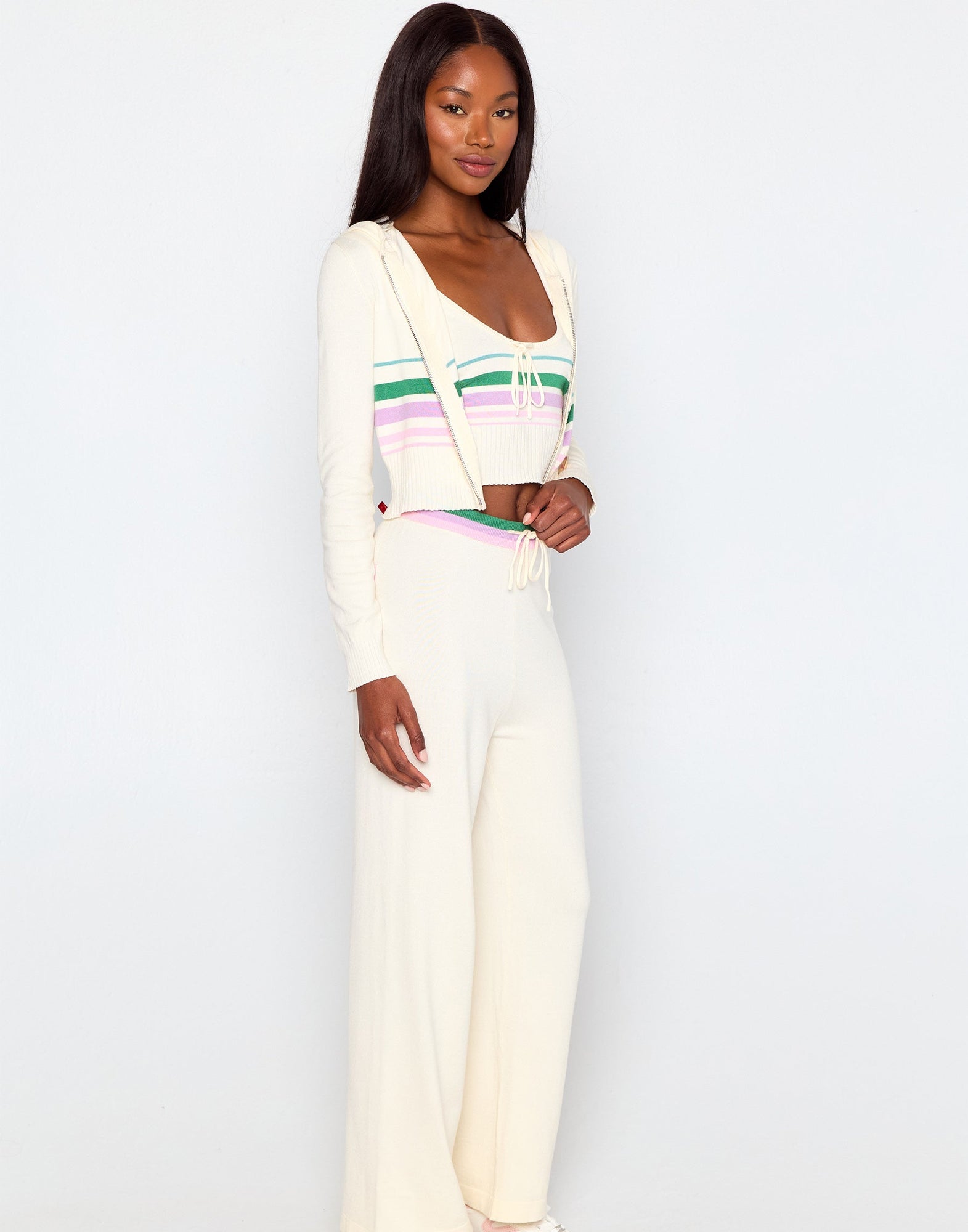 Woman wearing a white outfit with colorful stripes on a plain background