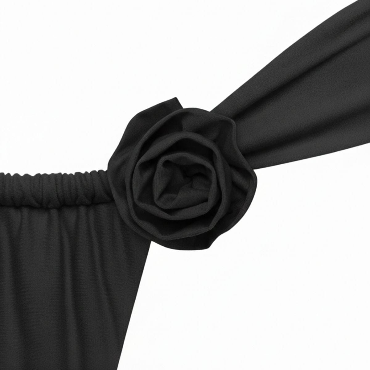 Charcoal fabric rose pin attached to dark gathered textile material.