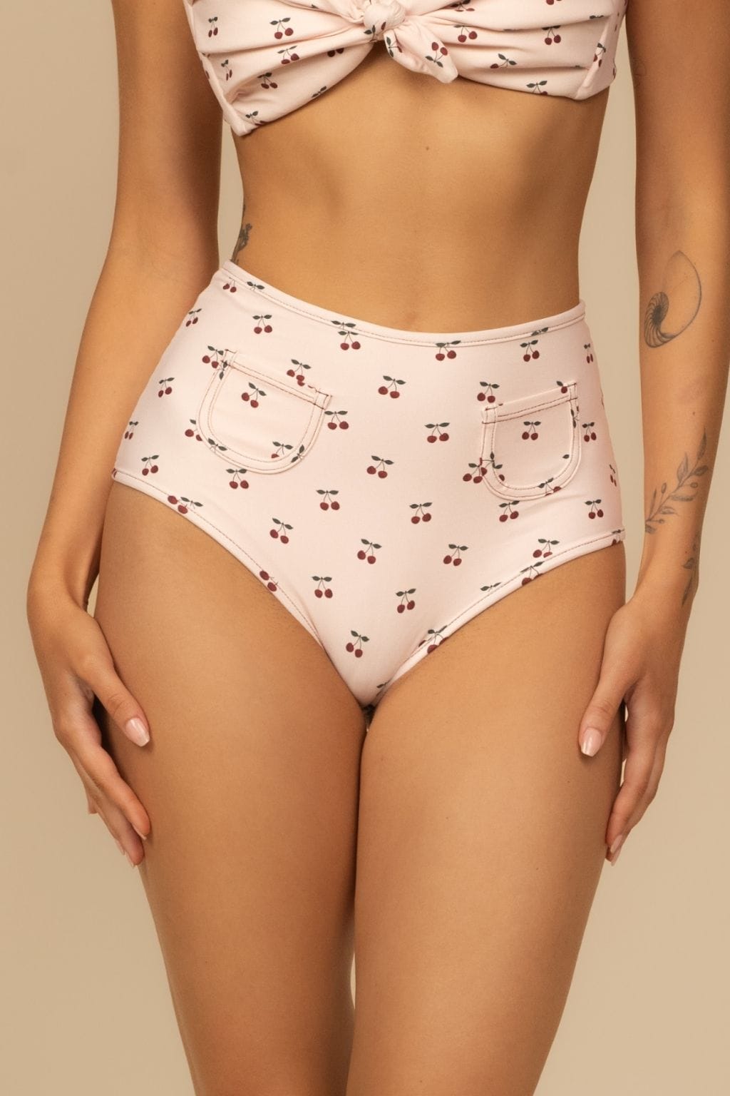 Beige bikini bottom with red cherry print and two front pockets.