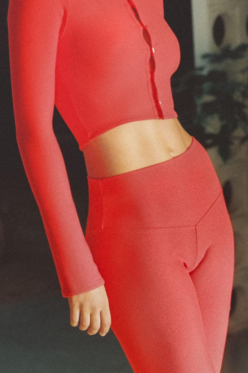 Red capri legging with long sleeves and cropped waistband, shown on a model from waist down.