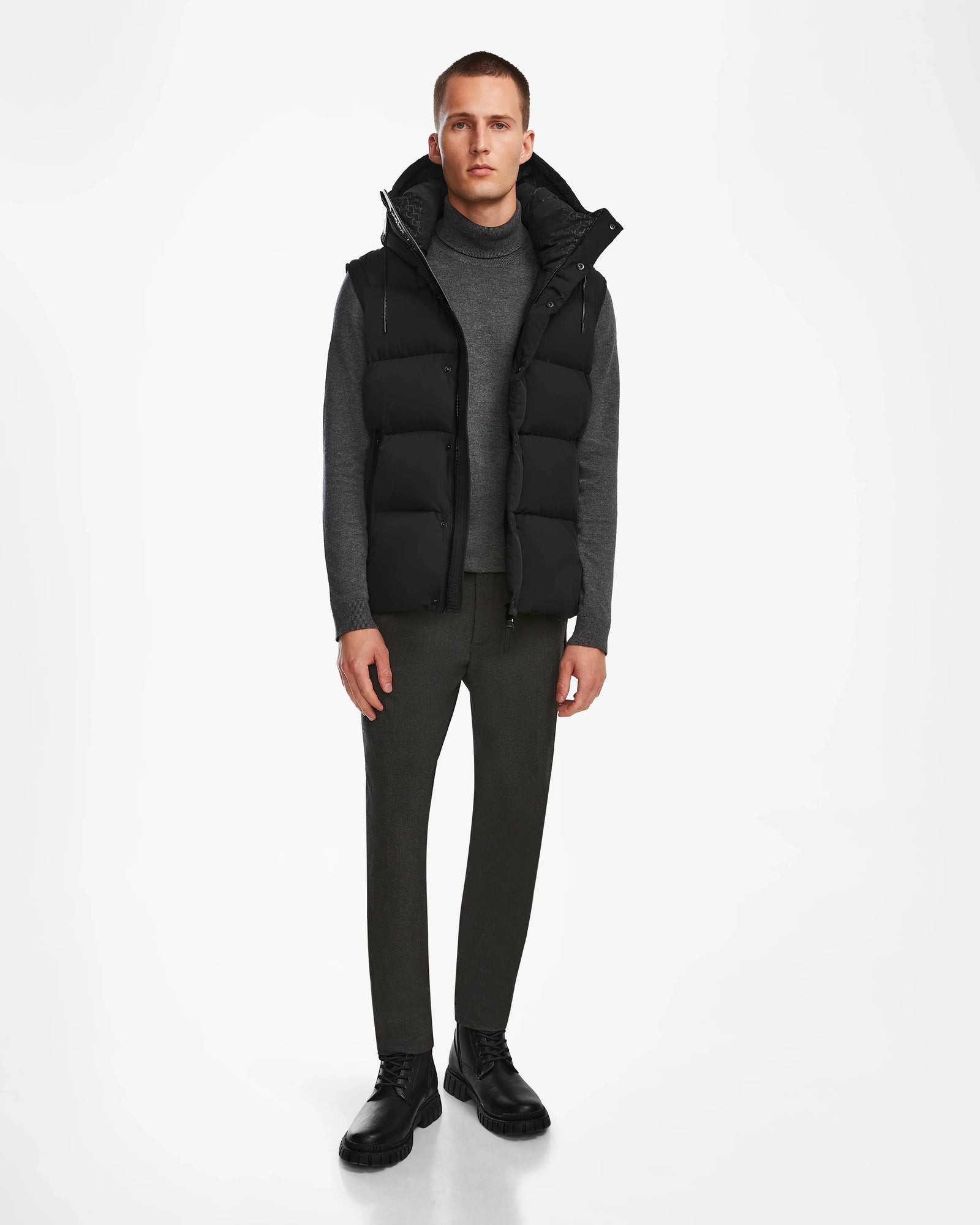 A man wearing the Rudsak BOBBY - 6124506 Black mens water-resistant quilted down puffer vest and pants.