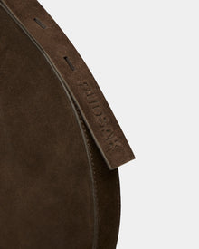 Close-up of the Rudsak LANISSA S - 8324520 Espresso, a brown suede hobo bag featuring a leather strap embossed with RUDSAK, set against a plain light grey background. This minimalist women’s crossbody bag is perfect for daily essentials.