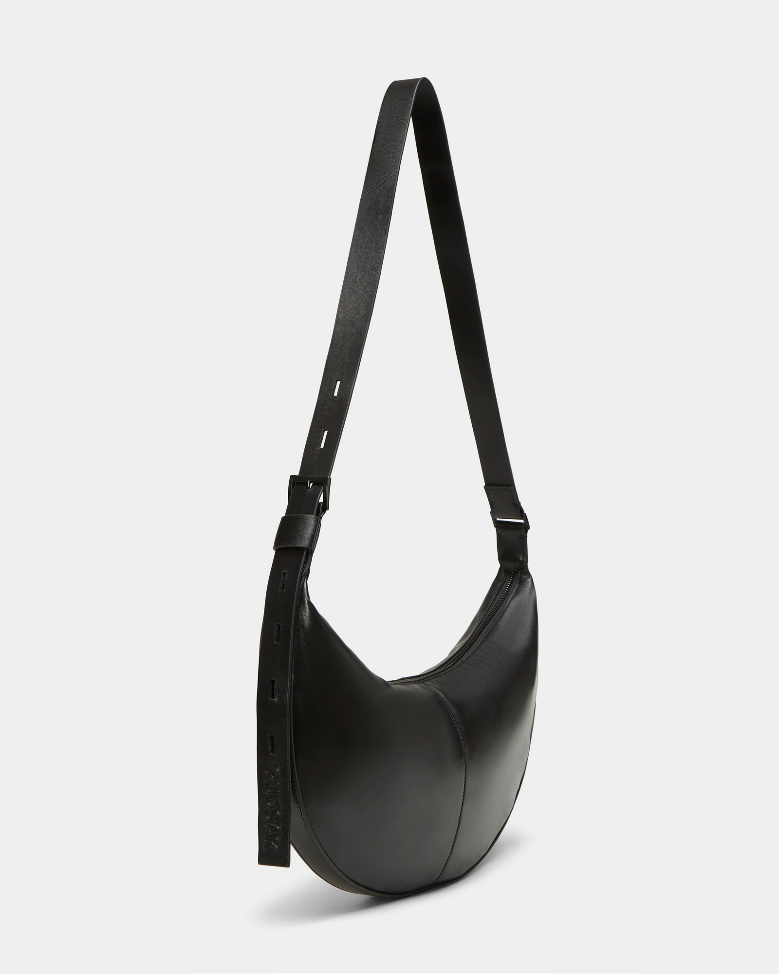 The Rudsak LANISSA - 8324505 Black is a black leather crescent-shaped women’s bag with an adjustable strap, shown on a white background. Wear it as a shoulder or crossbody for versatile, effortless style.