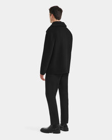 A man faces away wearing Rudsaks AIDEN - 6125558 Black, a mens wool-blend coat with removable faux shearling collar, styled with black trousers and boots against a white background.