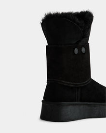 A close-up of the Rudsak INESA - L225026 Black women’s suede platform boot with lace-up front, black fur lining, decorative buttons, and visible stitching, shown on a plain white background.