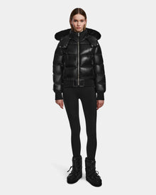 A woman stands facing forward wearing the Rudsak MAUDE Q-S - L124553 Black RDS-certified down jacket with a hood, paired with black leggings and winter boots against a plain white background.
