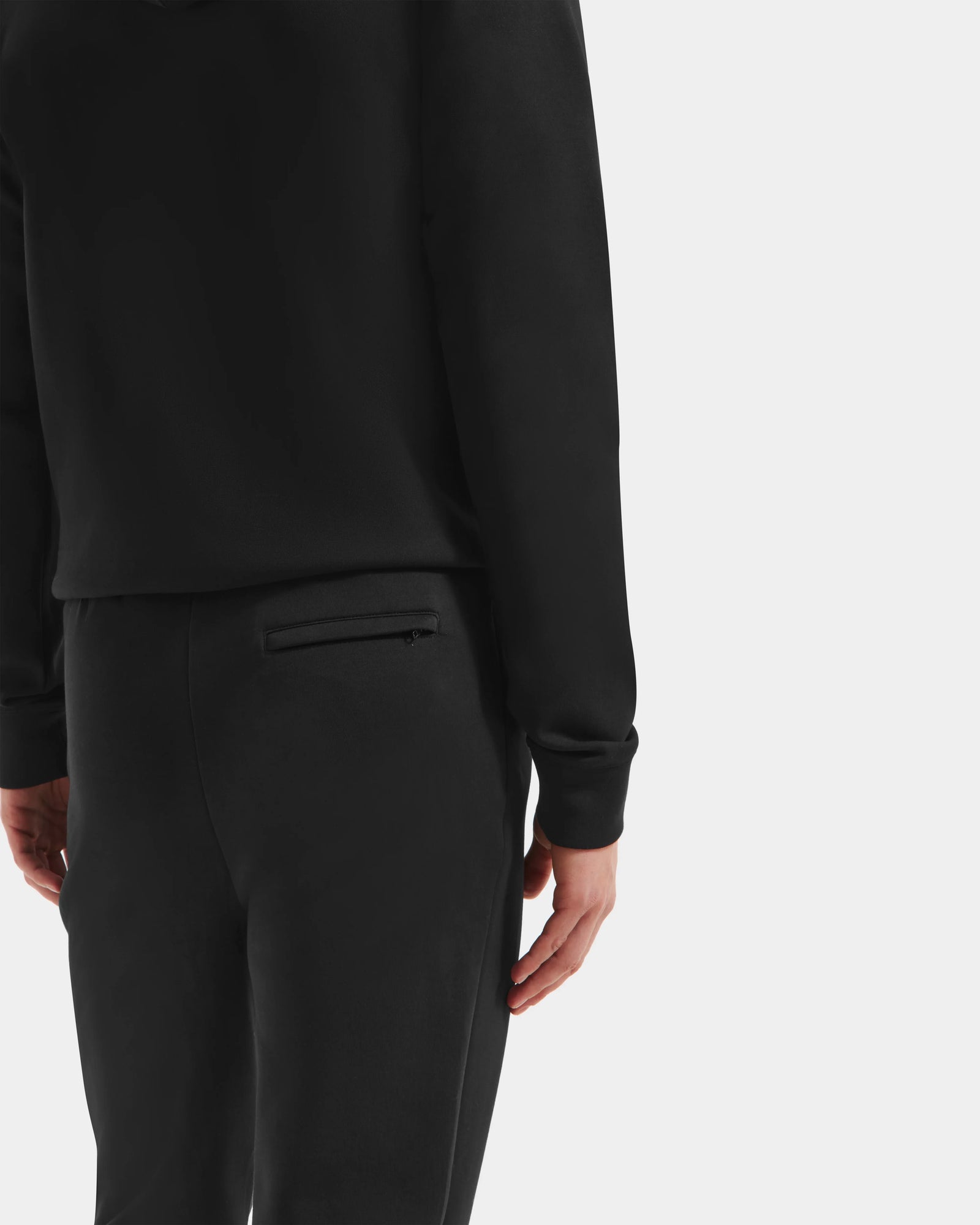 Wearing the Rudsak MAXTON - U525007 Black M hoodie and joggers, a person stands against a white background with their back and right arm visible, highlighting everyday comfort and effortless style.