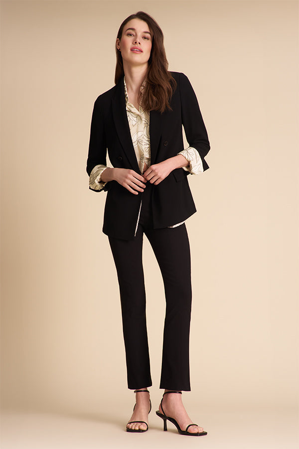 Person wearing black pants and a patterned top on a beige background | Exclude