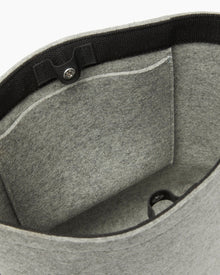 The graf lantz grey felt tote bag is made from sustainable materials, featuring black trim and a small front interior pocket for functionality. It has a button clasp to secure the top, and its soft fabric makes it perfect for daily use.