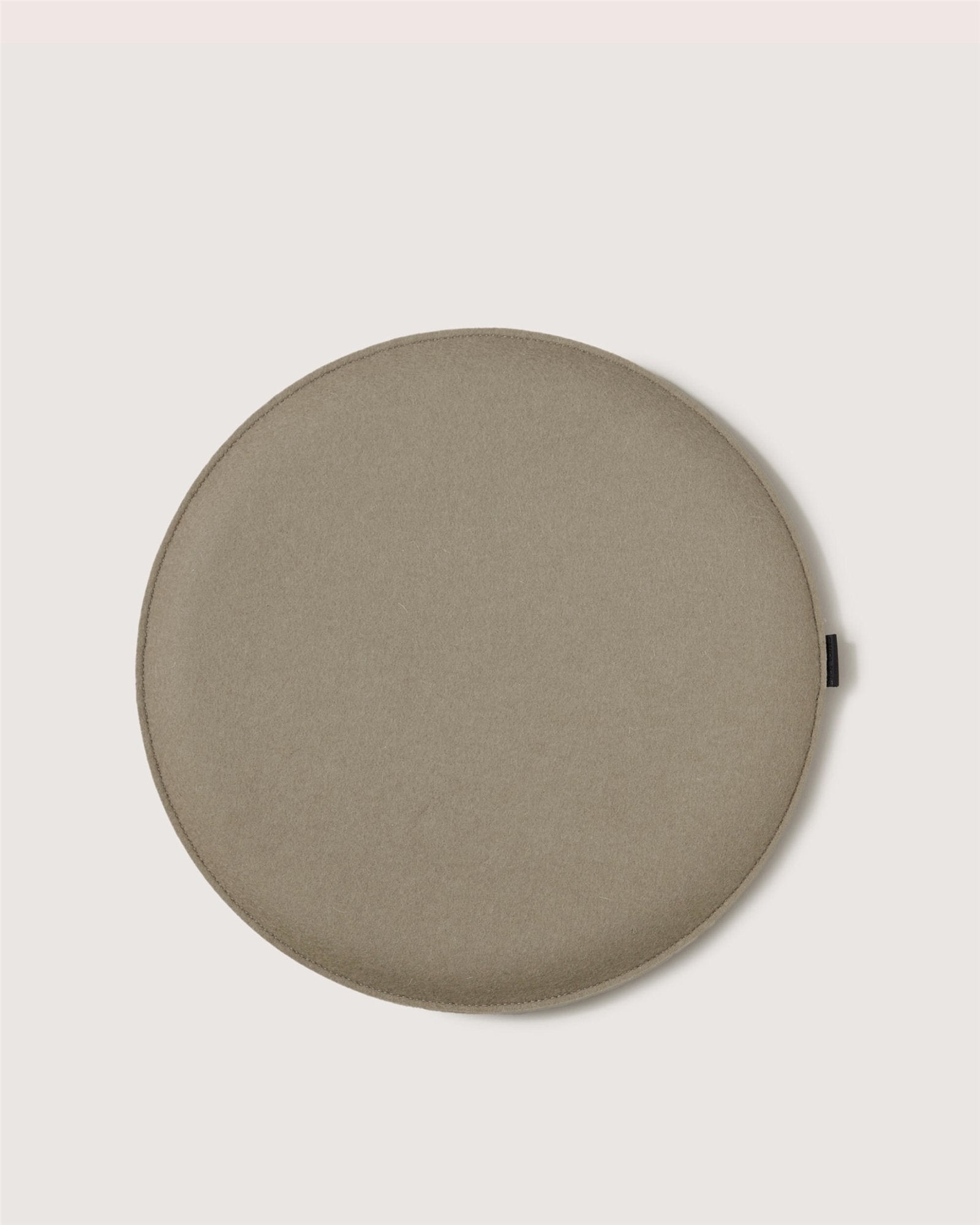 A round, flat, light brown cushion or pad by Graf Lantz with a smooth surface, resembling Zabuton seat cushions, placed on a plain light background.