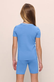 Model is wearing the Kids TENCEL Modal Unisex Short PJ Set in cornflower blue/white
