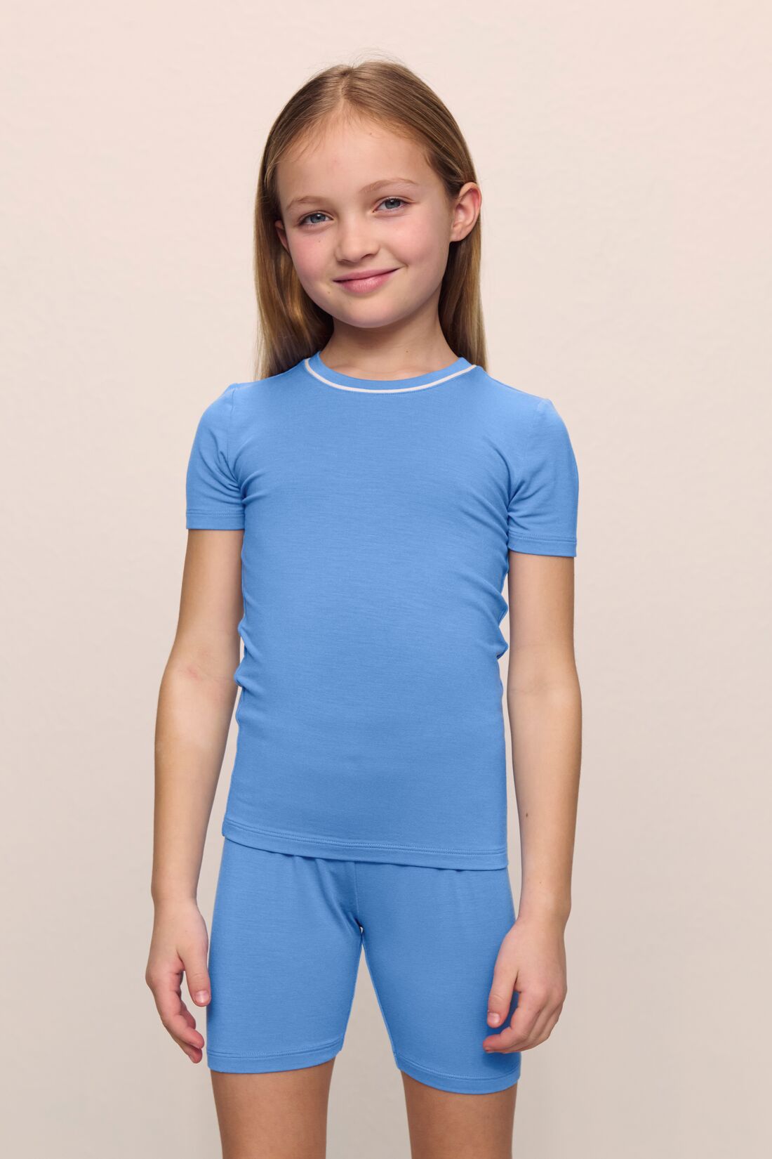 Model is wearing the Kids TENCEL Modal Unisex Short PJ Set in cornflower blue/white