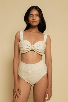 Cream textured bikini top with sweetheart neckline, bow detail at center, and thick shoulder straps.