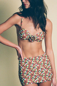 Micro skirt with multicolored ditsy floral print in red, yellow, and white on dark background.