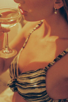 Woman wearing rose and gold striped bikini top with gathered center detail.