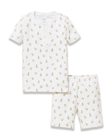 A young child with long brown hair smiles while wearing the Kid's Pima Snug Fit Short Set in Tres Chick, standing against a plain light background.