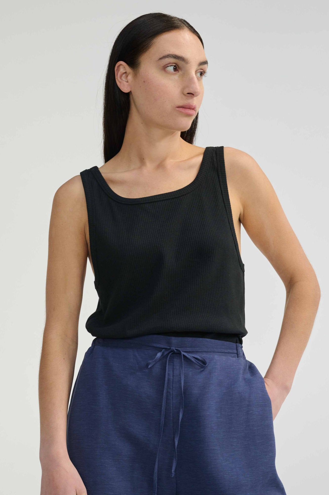 Woman wearing blank relaxed tank top against a light grey background