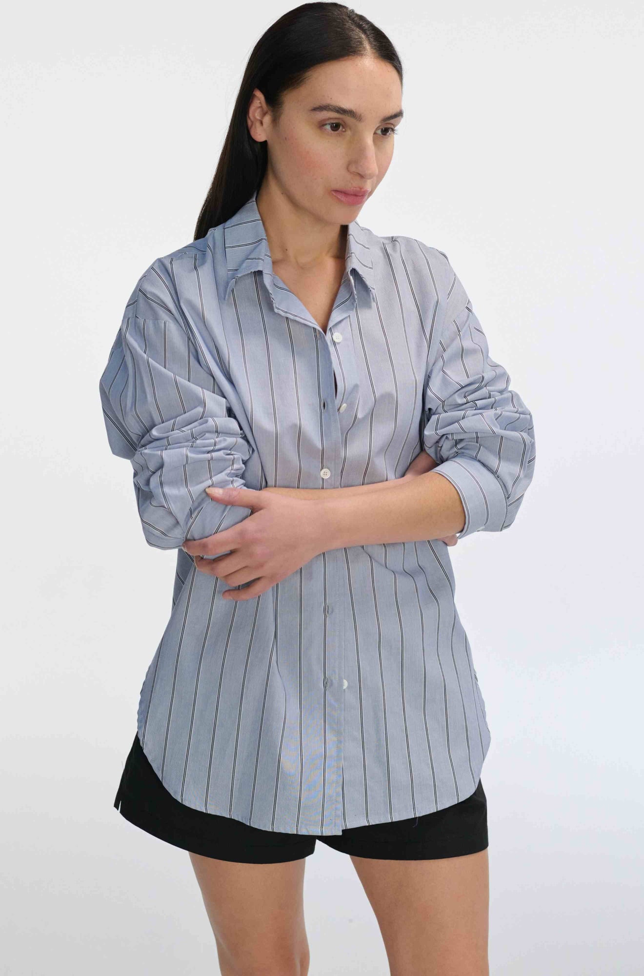 Woman wearing a blue striped shirt and black shorts on a white background