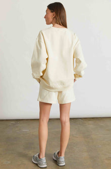 Woman wearing a yellow sweatshirt and matching sweatshorts