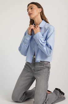 Woman wearing a light blue shirt and gray jeans on a white background