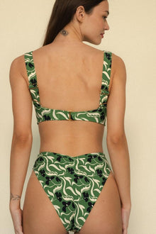 Green and cream floral bikini top with black accents, shown from back view on model.