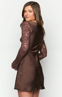 Girl looking back wearing a brown long sleeve mini dress.