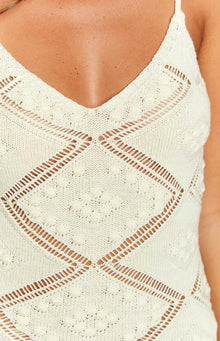 Close-up of the cream knit mini dress showing the V-neckline and diamond pattern with bobble stitches and openwork