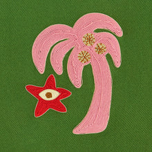Embroidered design of a palm tree and starfish on a green fabric background