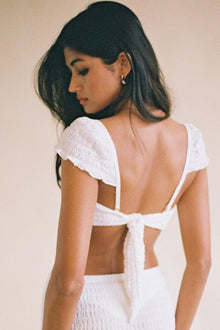 White bikini top with textured fabric, short sleeves, and tie-back closure shown from back view.