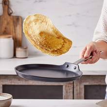 Golden pancake flipping in a nonstick skillet on a kitchen counter