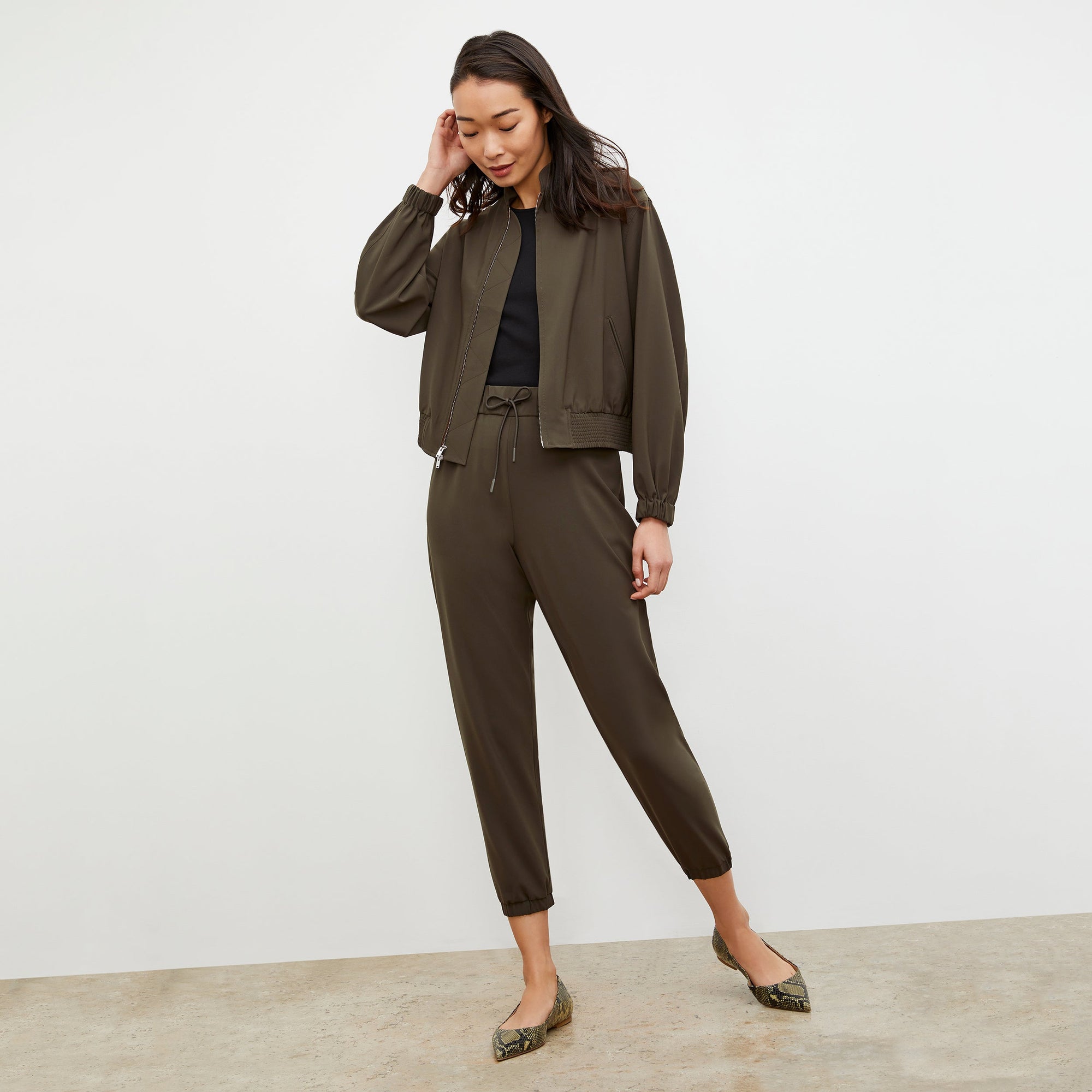 Back image of a woman standing wearing the Delaney Jogger—OrigamiTech in Olive | Lead